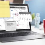 A laptop with pop-ups of a calendar and notepads, and a red coffee cup with the number 7 printed in white.
