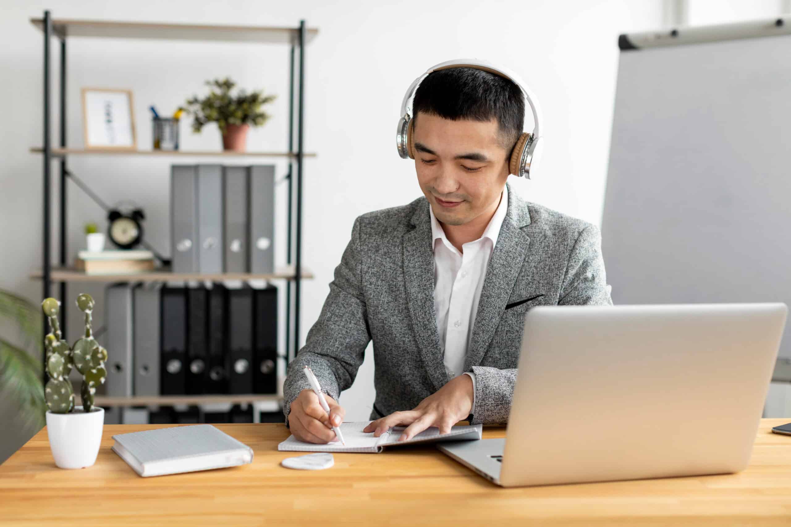A remote employee working with his headset on and writing something on a clipboard