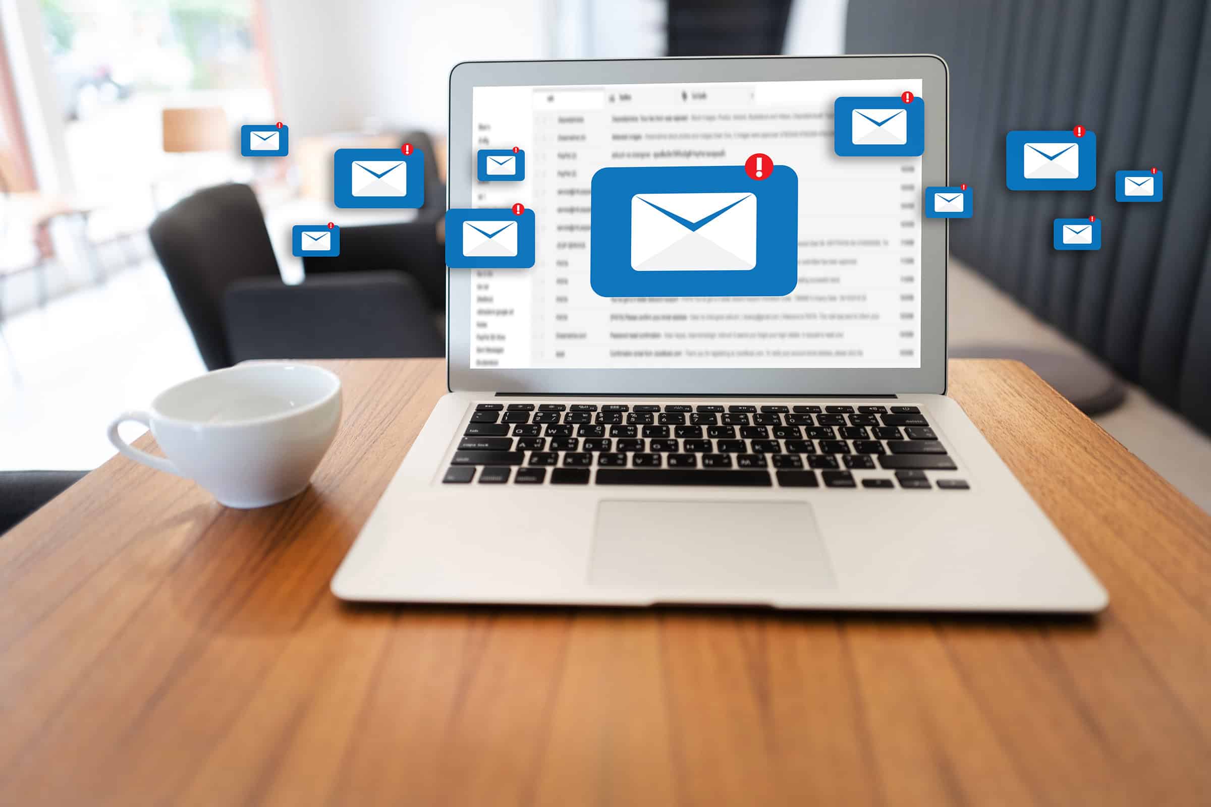 A coffee cup and a laptop with pop ups of an email graphic